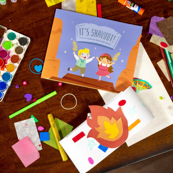 The Shavuot Illustrated Paperback Book on a table surrounded by colorful craft supplies.