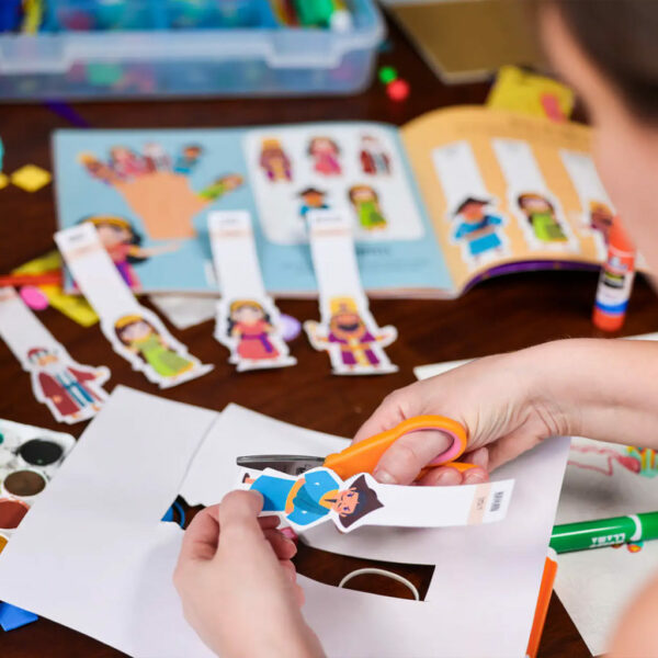 A child cutting out the finger puppet of Haman, a character from the Purim children's book